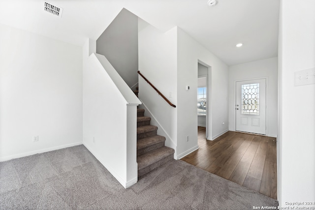 carpeted foyer entrance featuring baseboards, visible vents, wood finished floors, stairs, and recessed lighting