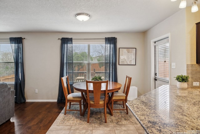 dining room with a textured ceiling, light wood finished floors, and baseboards