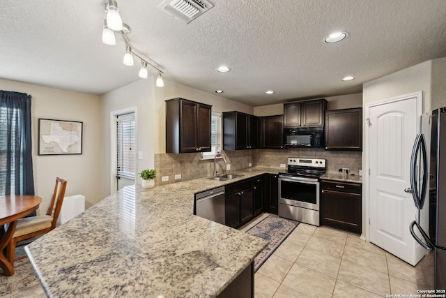 kitchen with stainless steel appliances, visible vents, a sink, light stone countertops, and a peninsula