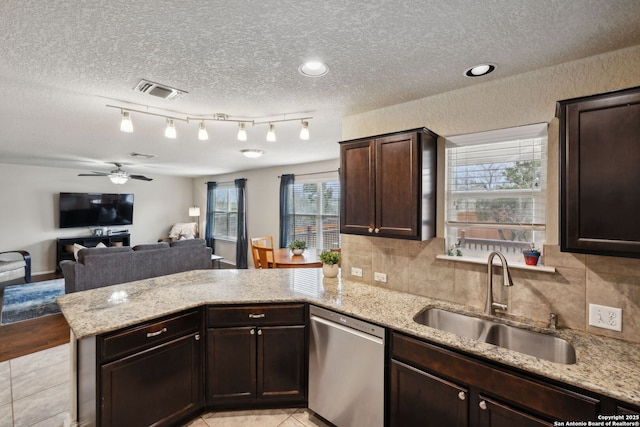 kitchen featuring dark brown cabinetry, a peninsula, a sink, open floor plan, and stainless steel dishwasher