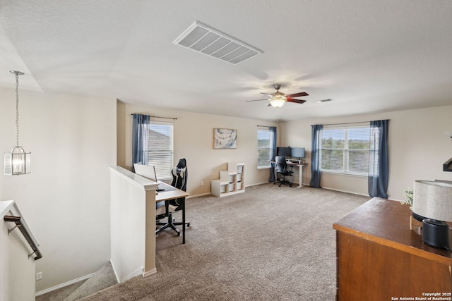 carpeted office space with baseboards, visible vents, and a ceiling fan