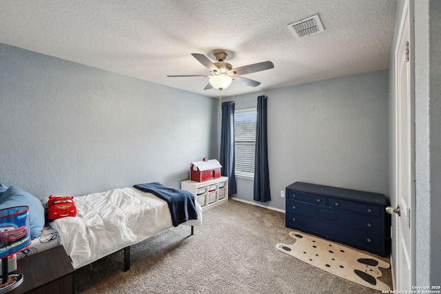 bedroom with a ceiling fan, carpet, visible vents, and a textured ceiling