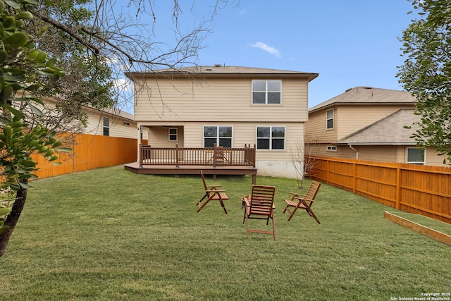 back of property with a deck, a yard, and a fenced backyard