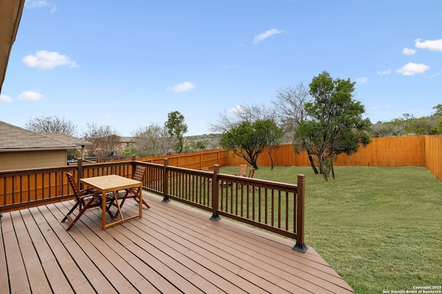 wooden terrace with outdoor dining space, a fenced backyard, and a yard