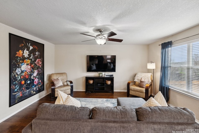 living room with ceiling fan, a textured ceiling, baseboards, and wood finished floors