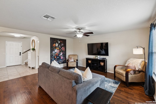 living room with baseboards, visible vents, arched walkways, stairway, and wood finished floors