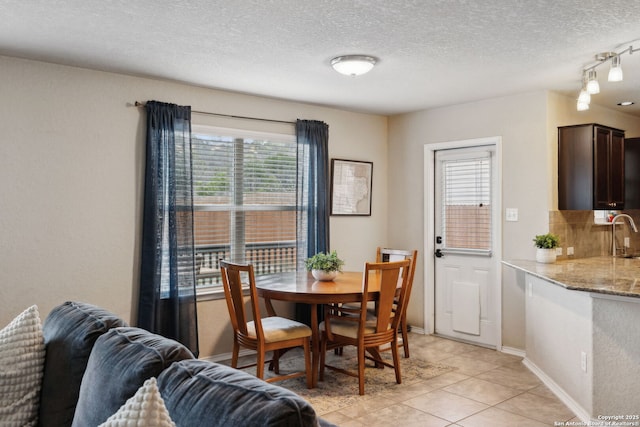 dining room with a textured ceiling, baseboards, and light tile patterned floors