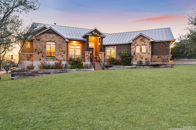 view of front of property with stone siding, metal roof, a front lawn, and a standing seam roof