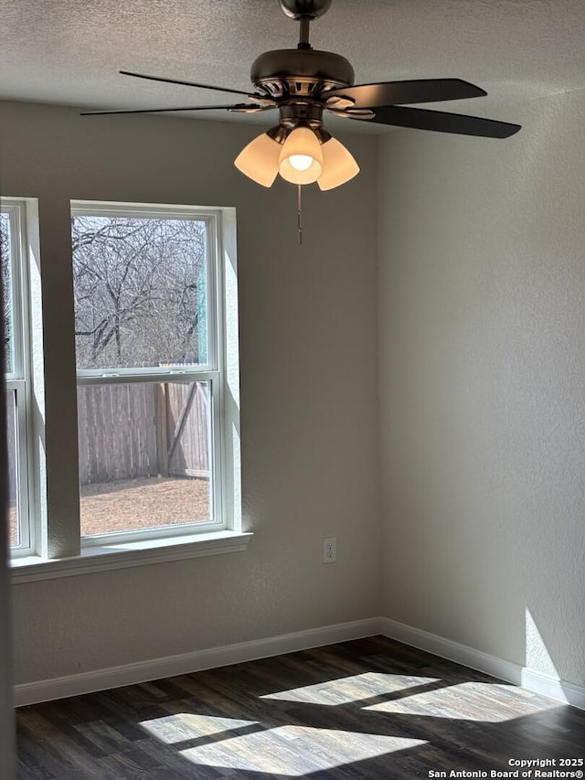 empty room featuring baseboards, dark wood finished floors, and a textured ceiling