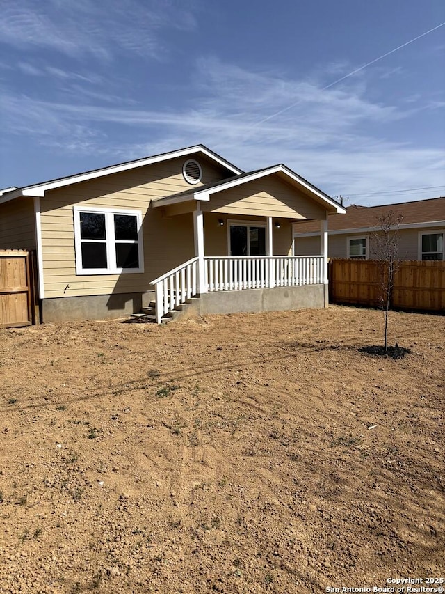 ranch-style home featuring covered porch and fence