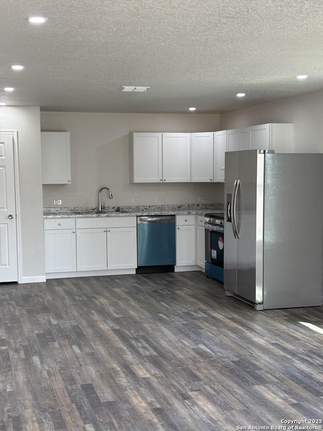 kitchen with stainless steel appliances, dark wood-type flooring, a sink, and white cabinetry