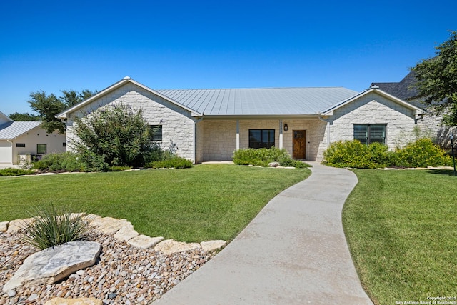 single story home with a front yard, stone siding, metal roof, and a standing seam roof