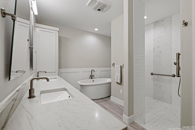 full bathroom featuring a freestanding tub, visible vents, a sink, and tiled shower