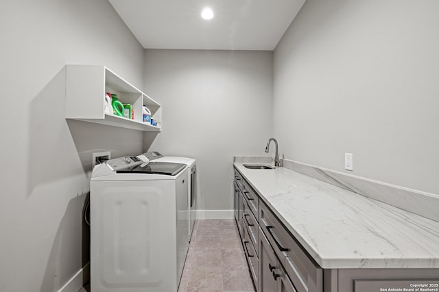 clothes washing area featuring cabinet space, baseboards, washer and clothes dryer, and a sink