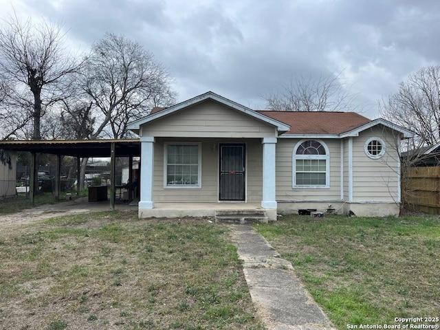 bungalow featuring fence, a porch, a carport, and a front yard