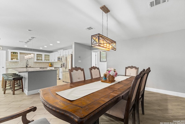 dining room with light wood-style floors, baseboards, and visible vents