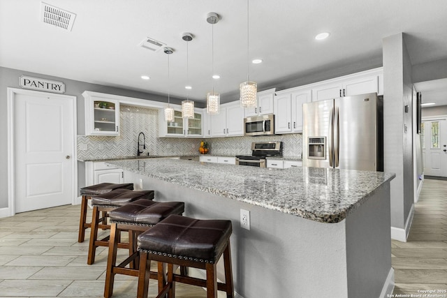 kitchen featuring visible vents, backsplash, appliances with stainless steel finishes, glass insert cabinets, and white cabinetry