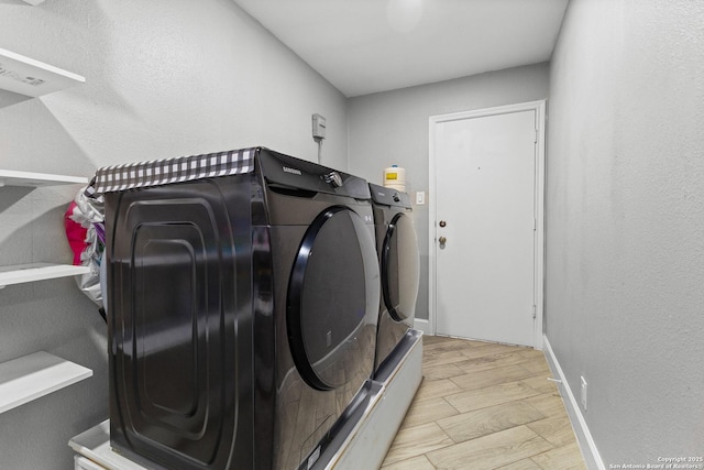 laundry room with laundry area, wood finish floors, washing machine and dryer, and baseboards