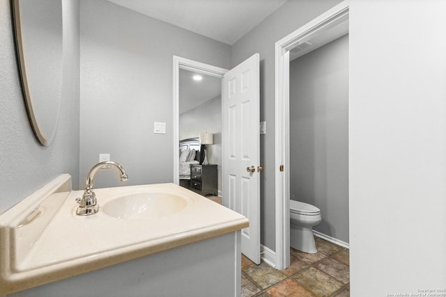 bathroom with baseboards, vanity, and toilet