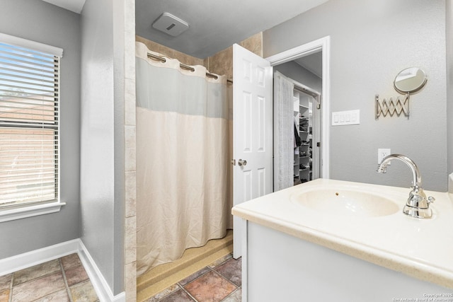 full bathroom with curtained shower, vanity, baseboards, and a spacious closet