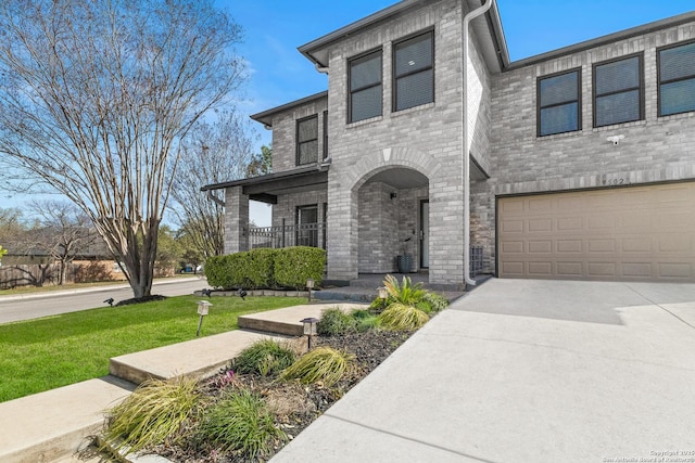 view of front facade with a garage, driveway, a front yard, and brick siding