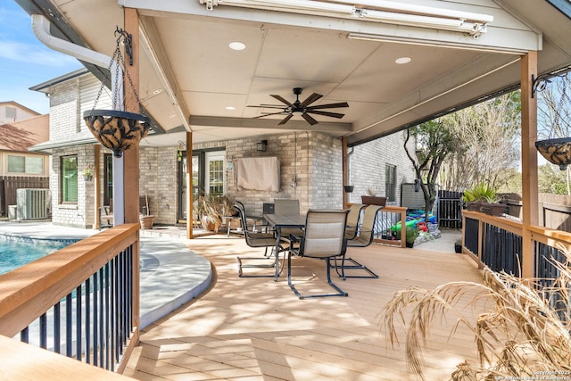 wooden terrace featuring central AC unit, a fenced in pool, a ceiling fan, fence, and outdoor dining space