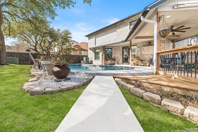 view of swimming pool with a fenced in pool, a ceiling fan, a fenced backyard, a yard, and central AC