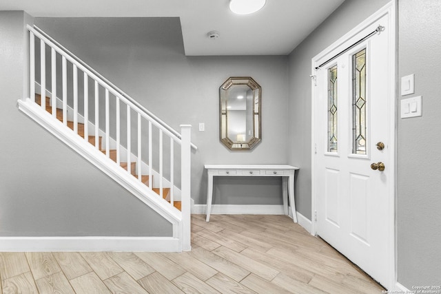 entrance foyer with stairs, wood finish floors, and baseboards