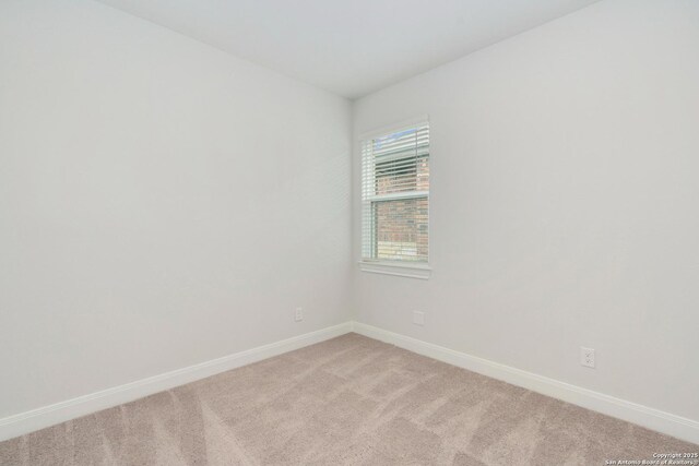 spare room featuring light carpet and baseboards