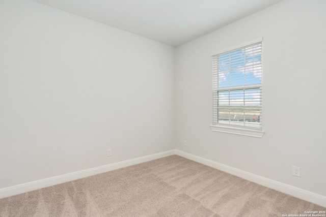 spare room featuring baseboards and light colored carpet