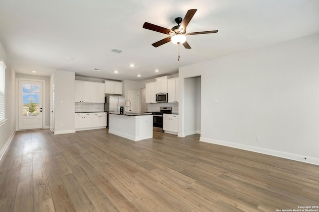 kitchen featuring open floor plan, appliances with stainless steel finishes, dark countertops, and tasteful backsplash