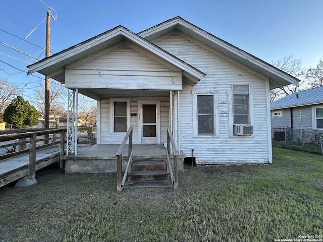 bungalow-style house featuring covered porch, fence, cooling unit, and a front yard