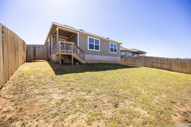 back of house with a yard and a fenced backyard