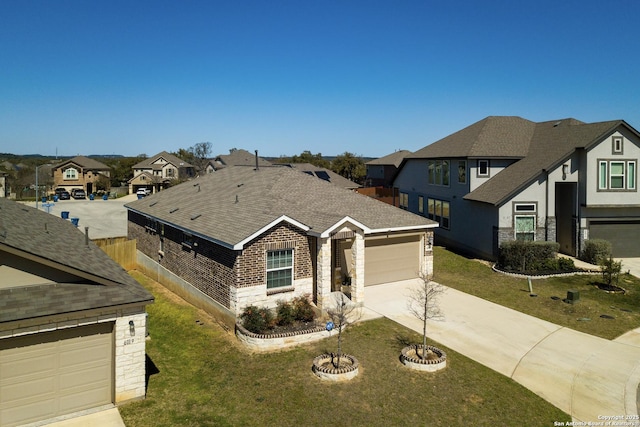 view of front facade featuring stone siding, concrete driveway, a residential view, and a front yard