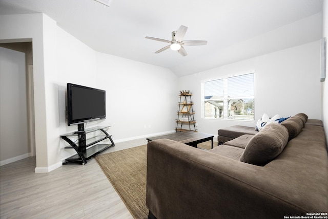 living area featuring light wood-style floors, baseboards, vaulted ceiling, and a ceiling fan