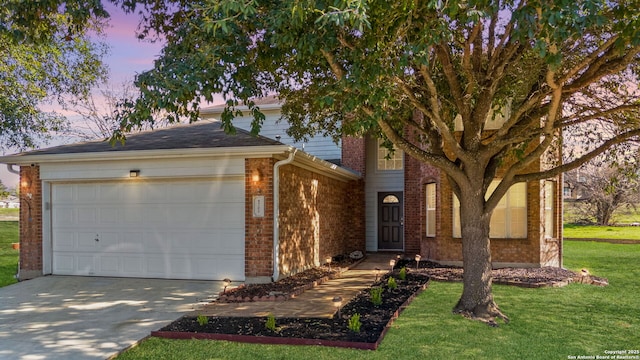 view of front facade with a garage, concrete driveway, brick siding, and a yard