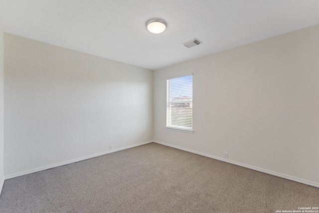 empty room featuring carpet, visible vents, and baseboards