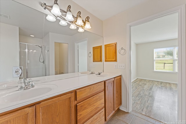 bathroom with double vanity, visible vents, tile patterned floors, a shower stall, and a sink