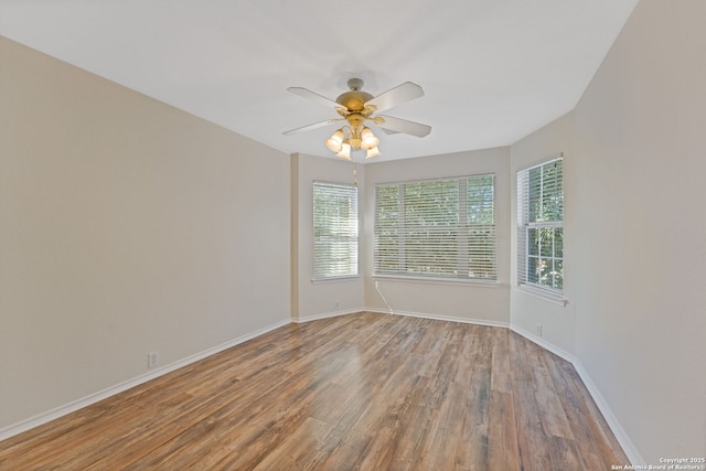 spare room featuring wood finished floors, a ceiling fan, and baseboards