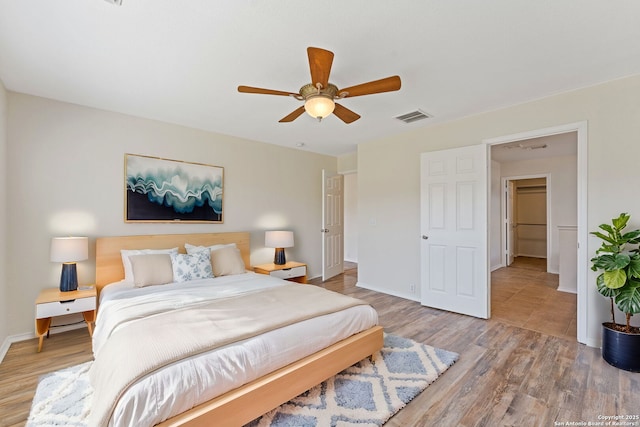 bedroom featuring ceiling fan, wood finished floors, visible vents, and baseboards