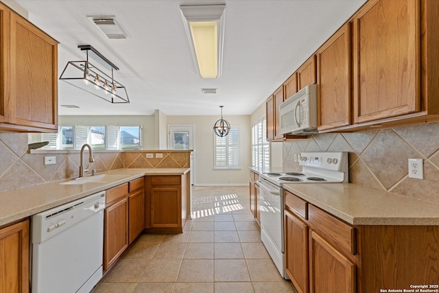 kitchen with white appliances, visible vents, brown cabinets, a sink, and light tile patterned flooring