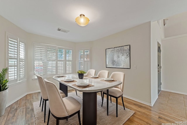 dining space with visible vents, light wood-style flooring, and baseboards