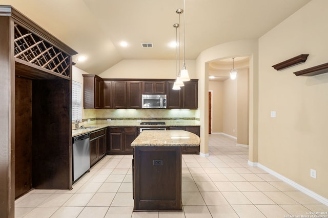 kitchen with light tile patterned floors, stainless steel appliances, dark brown cabinets, backsplash, and light stone countertops