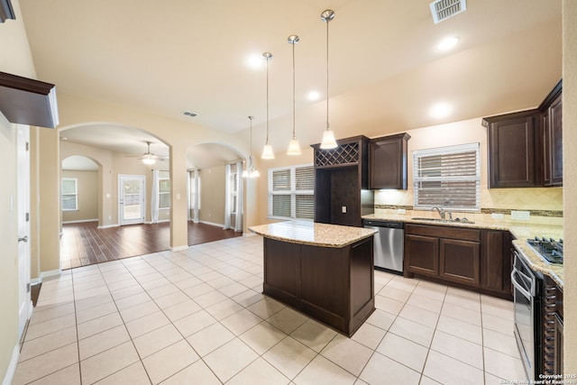 kitchen with arched walkways, light tile patterned floors, visible vents, open floor plan, and appliances with stainless steel finishes