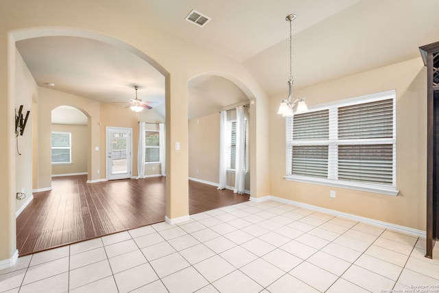 spare room featuring ceiling fan with notable chandelier, light tile patterned flooring, visible vents, and baseboards