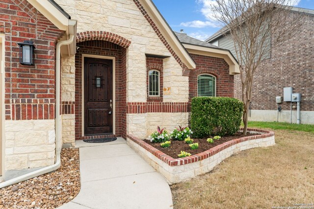 property entrance featuring stone siding, brick siding, and roof with shingles