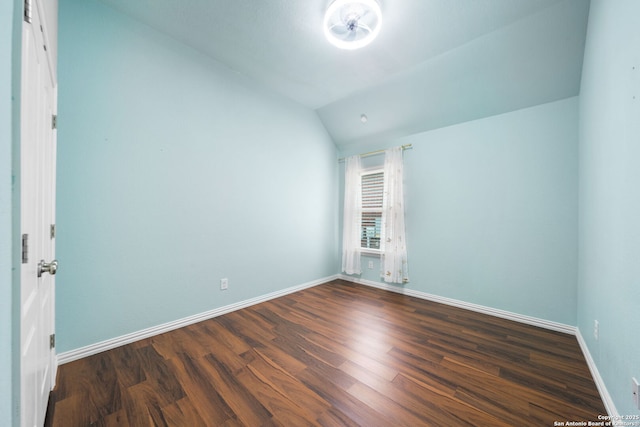 unfurnished room featuring baseboards, vaulted ceiling, and dark wood-type flooring