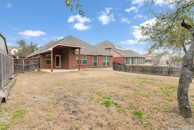 back of property with a patio area, brick siding, a yard, and a fenced backyard