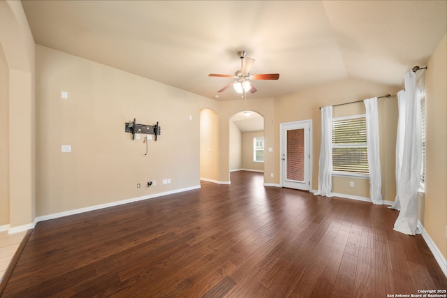 spare room with arched walkways, dark wood-style flooring, ceiling fan, and baseboards