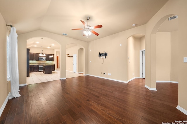 unfurnished living room featuring arched walkways, visible vents, ceiling fan, and wood finished floors